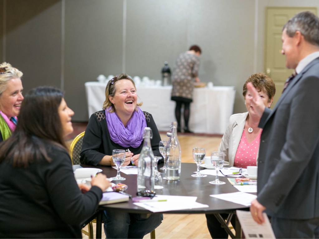 A group of people conjugate at a networking event and engage in conversations as they learn how to network.