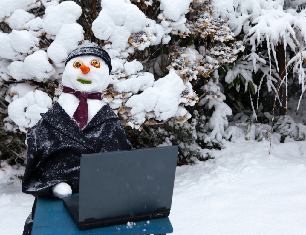 A snowman works on his computer showcasing how winter jobs are available to everyone.