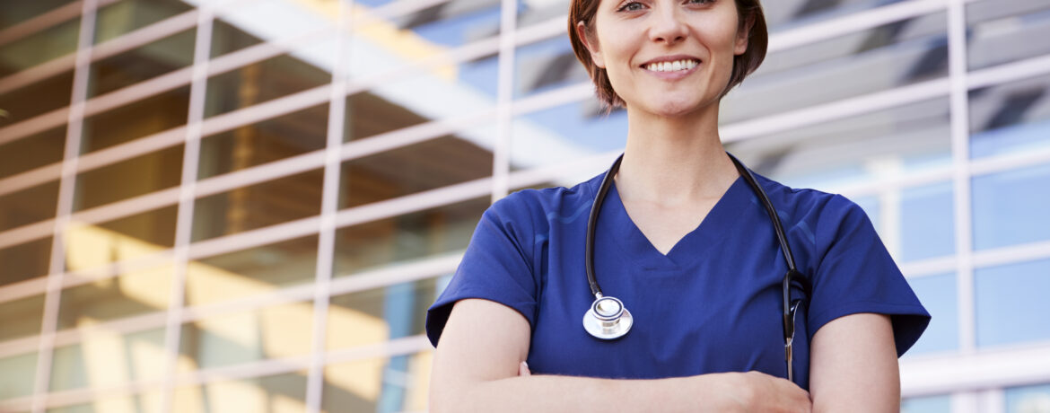 Smiling white female healthcare worker outdoors, waist up