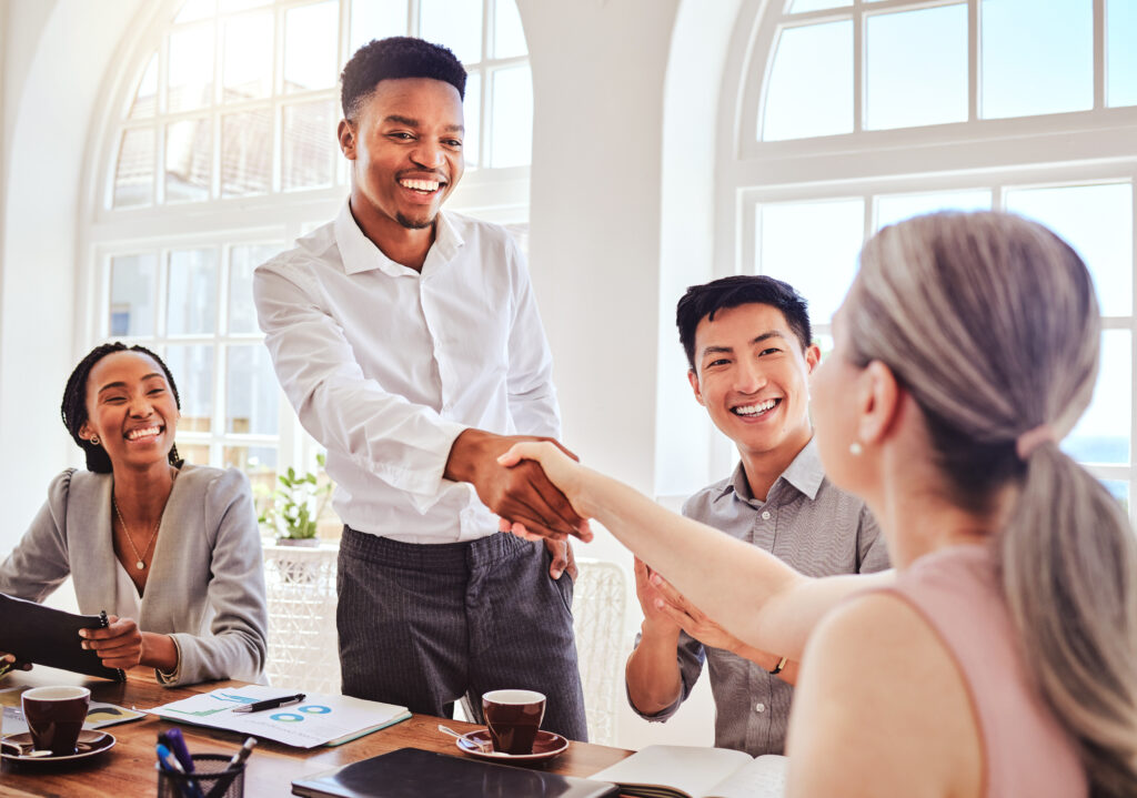 New hire shaking hands with team, using our top workplace etiquette tips.