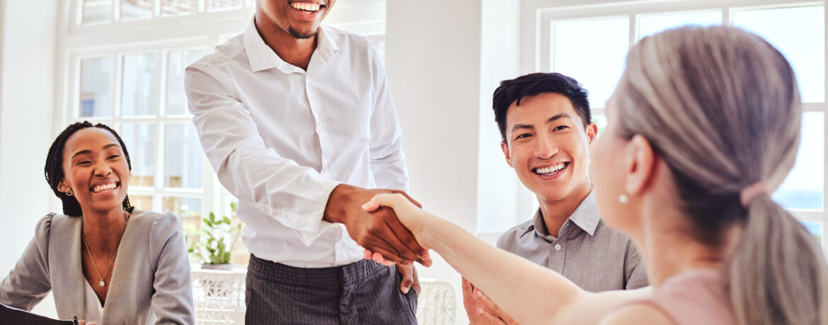 New hire shaking hands with team, using our top workplace etiquette tips.