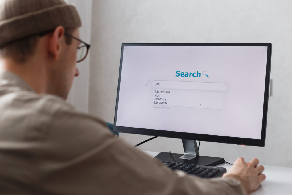 Unemployed man sitting at home on computer searching for jobs.