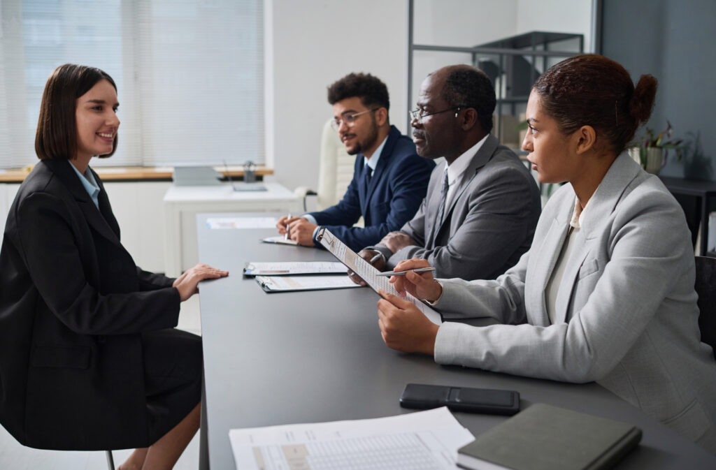 Professional woman interviewing for an office job with a panel of three interviewers.