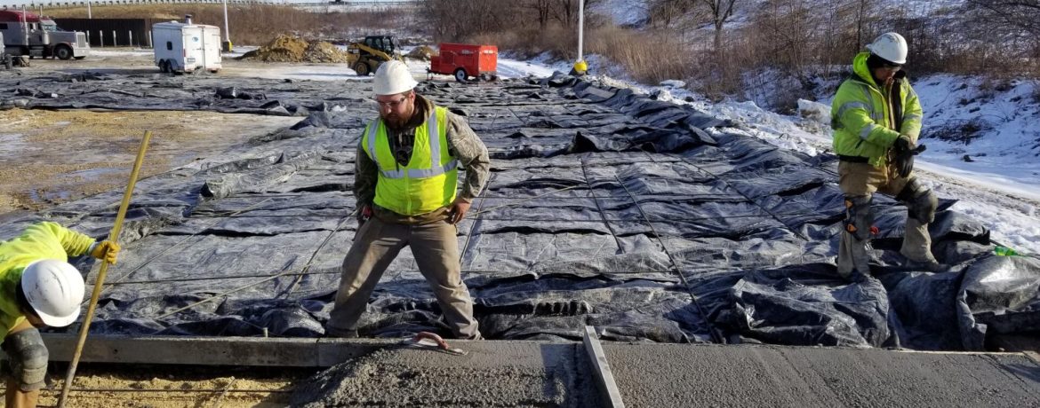 Concrete crew working on a winter job site in La Crosse, Wisconsin, leveling and finishing freshly poured concrete.